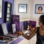 A portrait of Prince hangs on the wall of the home of Margo Davis as she looks over a collection of Prince memorabilia.