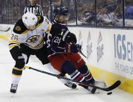 Boston Bruins' John-Michael Liles, left, and Columbus Blue Jackets' Oliver Bjorkstrand vie for a loose puck during the second period of an NHL hockey game Thursday, Oct. 13, 2016, in Columbus, Ohio. (AP Photo/Jay LaPrete)
