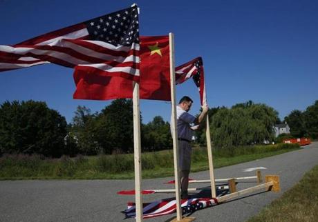 Chester, NH - 8/11/2016 - A man worked to right American and Chinese flags after a gust of wind blew them over shortly before the start of the Busche Academy Closing Ceremony in Chester, NH, August 11, 2016. (Jessica Rinaldi/Globe Staff) Topic: 17china 
