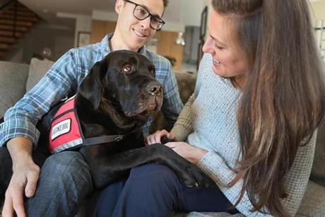 Jessica Kensky and her husband, Patrick Downes, play with Rescue, a service black Labrador.
