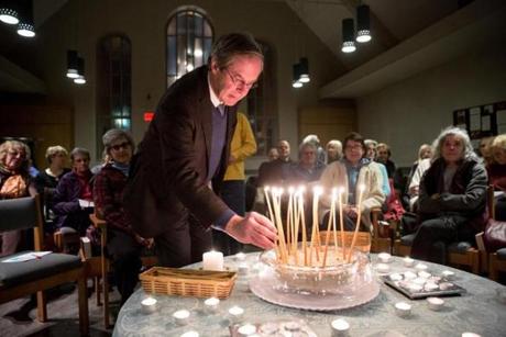 Charlie Bering lit a candle during a multifaith prayer service held Monday at Church of Good Shepherd in Watertown. 
