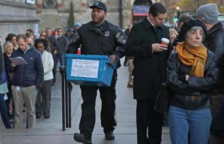 BOSTON, MA - 11/08/2016: A Boston Police Officer brings in a ballot box passing a line outside the Boston Public Library....The 2016 presidential election, voter turnout at polling places (David L Ryan/Globe Staff Photo) SECTION: METRO TOPIC 09turnout
