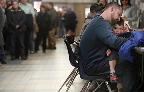 Manchester, NH, 11/07/16, David Gele, with his son Jaxson on his lap, registers to vote with long lines behind him. Long lines formed at Memorial High School/Ward 8. (Suzanne Kreiter/Globe staff)
