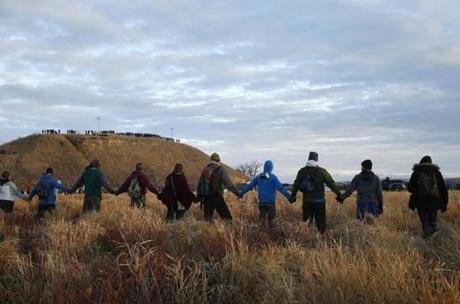 Protesters joined hands in prayer on Thursday as police lined the hill at Standing Rock during an ongoing dispute over the building of the Dakota Access Pipeline.
