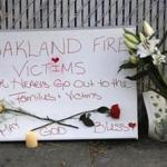 Signs and flowers adorned a fence near the site of a warehouse fire in Oakland, Calif. 