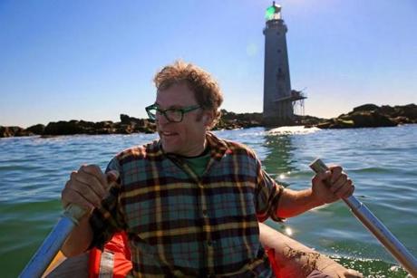 Dave Waller navigates a small dinghy past rocks surrounding the lighthouse he and his wife bought at auction in 2013.
