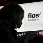 A woman looks at her phone in front of a Verizon Fios sign in Times Square in New York March 11, 2016. REUTERS/Brendan McDermid