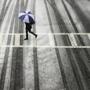 A pedestrian crosses a road in Boston amid light traffic during a storm.