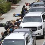 People take cover outside the Fort Lauderdale airport Friday after a shooter opened fire. 