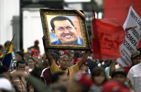 A supporter of Venezuelan President Nicolas Maduro holds a portrait of late Venezuelan President Hugo Chavez during a demonstration march to the Miraflores presidential palace in Caracas on April 7, 2016. Supporters of Venezuelan President Nicolas Maduro mobilized to ask him to block an amnesty law promoted by the opposition, and already approved in the opposition-controlled Parliament, but that still requires presidential approval. / AFP / JUAN BARRETO / JUAN BARRETO (Photo credit should read JUAN BARRETO/AFP/Getty Images)
