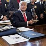 WASHINGTON, DC - FEBRUARY 7: (AFP OUT) U.S. President Donald Trump holds up a statue he received as a gift while meeting with county sheriffs in the Oval Office of the White House on February 7, 2017 in Washington, DC. The Trump administration will return to court Tuesday to argue it has broad authority over national security and to demand reinstatement of a travel ban on seven Muslim-majority countries that stranded refugees and triggered protests. (Photo by Andrew Harrer - Pool/Getty Images)