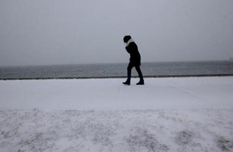  A woman walks along Pleasure Bay in South Boston against the strong winds. (David L. Ryan/Globe Staff)
