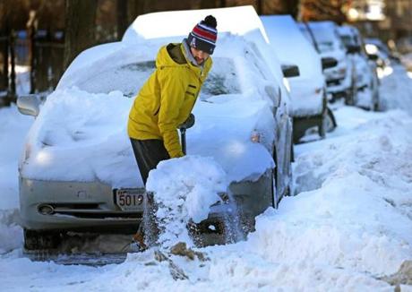 Kyle Tildsley shovels snow from a car parked in Boston.
