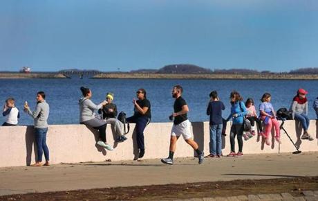 People lined the wall along Pleasure Bay in South Boston to enjoy the warm weather Friday. 
