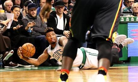 Celtics guard Marcus Smart slides out of bounds ? near Patriots receiver/spectator Julian Edelman ? during the C?s loss to the Hawks at TD Garden Monday.

