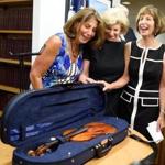 Amy, Nina, and Jill Totenberg view the stolen Stradivarius violin belonging to their late father, renowned violinist Roman Totenberg, at a news conference in August 2015.
