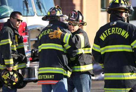 A Watertown firefighter hugged a fellow firefighter as the body of fallen Watertown firefighter Joseph Toscano arrived at the State Medical Examiners Office. 
