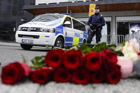 A police officer stands next to candles and flowers placed near the department store Ahlens following a suspected terror attack in central Stockholm, Sweden, Saturday, April 8, 2017. A Swedish prosecutor says a person has been formally identified as a suspect 