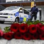 A police officer stands next to candles and flowers placed near the department store Ahlens following a suspected terror attack in central Stockholm, Sweden, Saturday, April 8, 2017. A Swedish prosecutor says a person has been formally identified as a suspect 