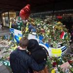 A couple hugged in front of a flower-covered police car at the site of last week?s attack.
