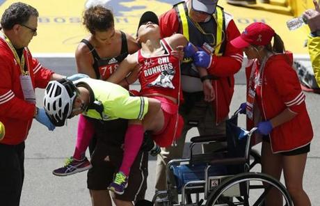 slider Boston, Massachusetts -- 4/17/2017 - Bibo Gao (C) is helped across the finish line of the 121st Boston Marathon and into a wheelchair by an EMS officer and a fellow runner. (Jessica Rinaldi/Globe Staff) Topic: Marathonpics Reporter: 
