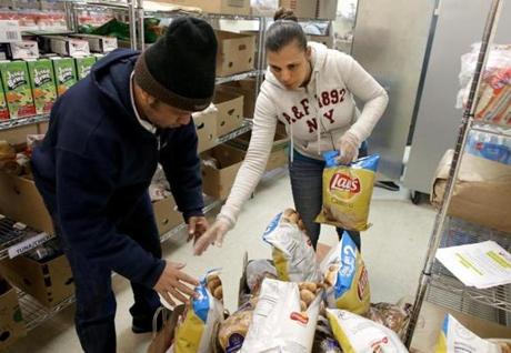 Volunteer Paillant Bod (left) and Jacelys de Pena pack groceries at the Catholic Charities Archdiocese of Boston Yawkey Center food pantry in Dorchester. 
