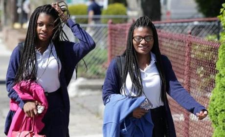 Mya Cook, left, and her sister Deanna Cook, right, attend Mystic Valley Regional Charter School and have served multiple detentions for wearing hair extensions.
