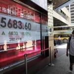 A man walked past an electronic board showing stock prices in Hong Kong on Monday. A rally led to three Chinese real-estate tycoons increasing their wealth by $5.4 billion.