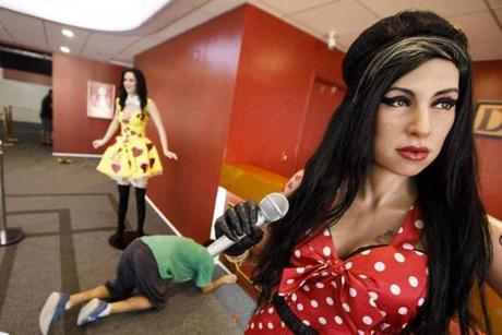 A laborer stapled carpeting next to wax figures of pop singers Katie Perry and Amy Winehouse at the Dreamland Wax Museum in Boston.
