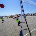 Ball and goalie are airborne at the Boston Beach Soccer Tournament Series at Nantasket Beach.
