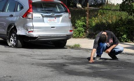 An unidentified man placed his hand where two people were killed after gunshots were fired and a car crashed in Dorchester on Thursday.
