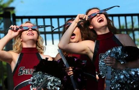 ECLIPSE SLIDER1 Saluki cheerleaders try out eclipse glasses that they were giving out to visitors to Saluki Stadium on the campus of Southern Illinois University Carbondale, Ill., on Monday, Aug. 21, 2017. Scientists said Monday's total eclipse would cast a shadow that would race through 14 states including Illinois. (Robert Cohen/St. Louis Post-Dispatch via AP)
