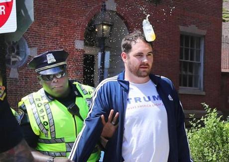 A police officer escorted a participant in Saturday?s ?free speech? rally away from the scene as a water bottle was headed in his direction.
