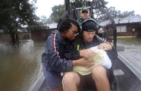 HARVEY SLIDER5 HOUSTON, TX - AUGUST 28: Shardea Harrison looks on at her 3 week old baby Sarai Harrison being held by Dean Mize as he and Jason Legnon used his airboat to rescue them from their home after the area was inundated with flooding from Hurricane Harvey on August 28, 2017 in Houston, Texas. Harvey, which made landfall north of Corpus Christi late Friday evening, is expected to dump upwards to 40 inches of rain in Texas over the next couple of days. (Photo by Joe Raedle/Getty Images)

