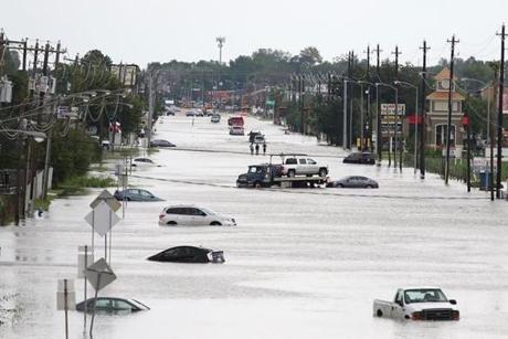A car gets towed while men walk in the flooded waters of Telephone Road in Houston.
