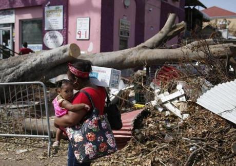 A woman carried a child and emergency water Tuesday as she passed debris from Hurricane Irma strewn in Cruz Bay, Virgin Islands.
