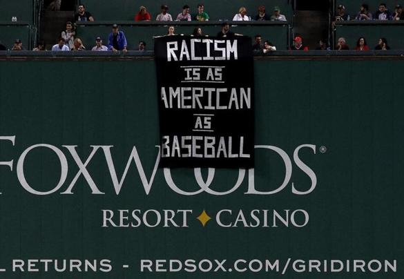 A banner is unfurled over the Green Monster during the fourth inning.