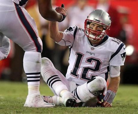 Tampa, FL: October 5, 2017: Patriots quarterback Tom Brady looked a litle dazed as he is helped off the turf by OL Marcus Cannon after being knocked down hard. The New England Patriots visited the Tampa Bay Buccaneers in a regular season Thursday Night NFL football game at Raymond James Stadium. (Jim Davis/Globe Staff). 
