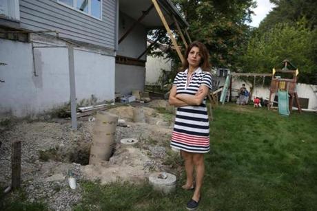 Homeowner Marjan Sadegh in the backyard of her Newton home, where the remains of a former deck and misplaced pilings sit, the result of a contract with Lowe?s for a new deck.
