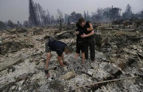 WILDFIRES SLIDER Michael Pond, left, looks through ashes as his wife Kristine, center, gets a hug from Zack Thurston, their daughter's boyfriend, while they search the remains of their home destroyed by fires in Santa Rosa, Calif., Monday, Oct. 9, 2017. (AP Photo/Jeff Chiu)
