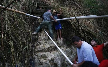 Following the destruction caused by Hurricane Maria, men In Puerto Rico rigged PVC pipes to collect water from a spring.

