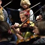 Violinist Johanna Szarkowski (center) focuses as she and her fellow members of the Melrose Symphony Orchestra follow the lead of Music director Yoichi Udagawa.