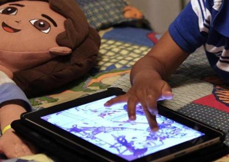 FILE - In this Friday, Oct. 21, 2011, file photo, a child plays with an iPad in his bedroom. Parents of small children have long been hearing about the perils of ?screen time.? And with more screens, it?s only getting worse. But working, taking care of children and remembering to eat is exhausting. Parents need those minutes of quiet. So maybe it?s time to relax a little. (AP Photo/, File)
