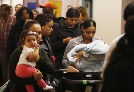Katie De Andrade of Dorchester (right) cradled her 3- month-old son Xander De Pina as she waited for a chance to be in the lottery to live at The Beverly on Court Street.
