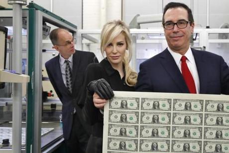Treasury Secretary Steven Mnuchin, right, and his wife Louise Linton, hold up a sheet of new $1 bills, the first currency notes bearing his and U.S. Treasurer Jovita Carranza's signatures, Wednesday, Nov. 15, 2017, at the Bureau of Engraving and Printing (BEP) in Washington. The Mnuchin-Carranza notes, which are a new series of 2017, 50-subject $1 notes, will be sent to the Federal Reserve to issue into circulation. At left is BEP Director Leonard Olijar. (AP Photo/Jacquelyn Martin)
