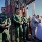 SAN YSIDRO, CA - NOVEMBER 18: Brian Houston, who lives in San Diego, kisses his new bride Evelia Reyes, who lives in Mexico with her daughter Alexis, while Border Patrol agents look on at the U.S. Mexico border November 18, 2017 in San Ysidro, California. The event, 