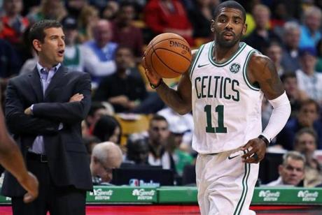 Boston, MA: October 2, 2017: The Celtics Kyrie Irving (right) dribbles by head coach Brad Stevens (left) during first quarter action. The Boston Celtics hosted the Charlotte Hornets in a pre season NBA basketball game at the TD Garden. (Jim Davis/Globe Staff).
