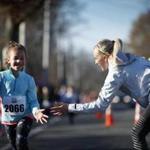 New York City Marathon winner Shalane Flanagan greeted Elise Rowland, 8, of Marblehead, at the end of a 1-mile kids? run Saturday in her hometown of Marblehead.