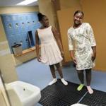 Nia Simpson, 16, left, and Regina Mendez, 16, try on their new dresses in the locker room. A group of girls received party dresses at the Boys and Girls Club of Boston.
