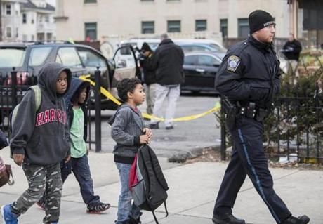A Boston police officer escorted a group of school children past the shooting scene. 

